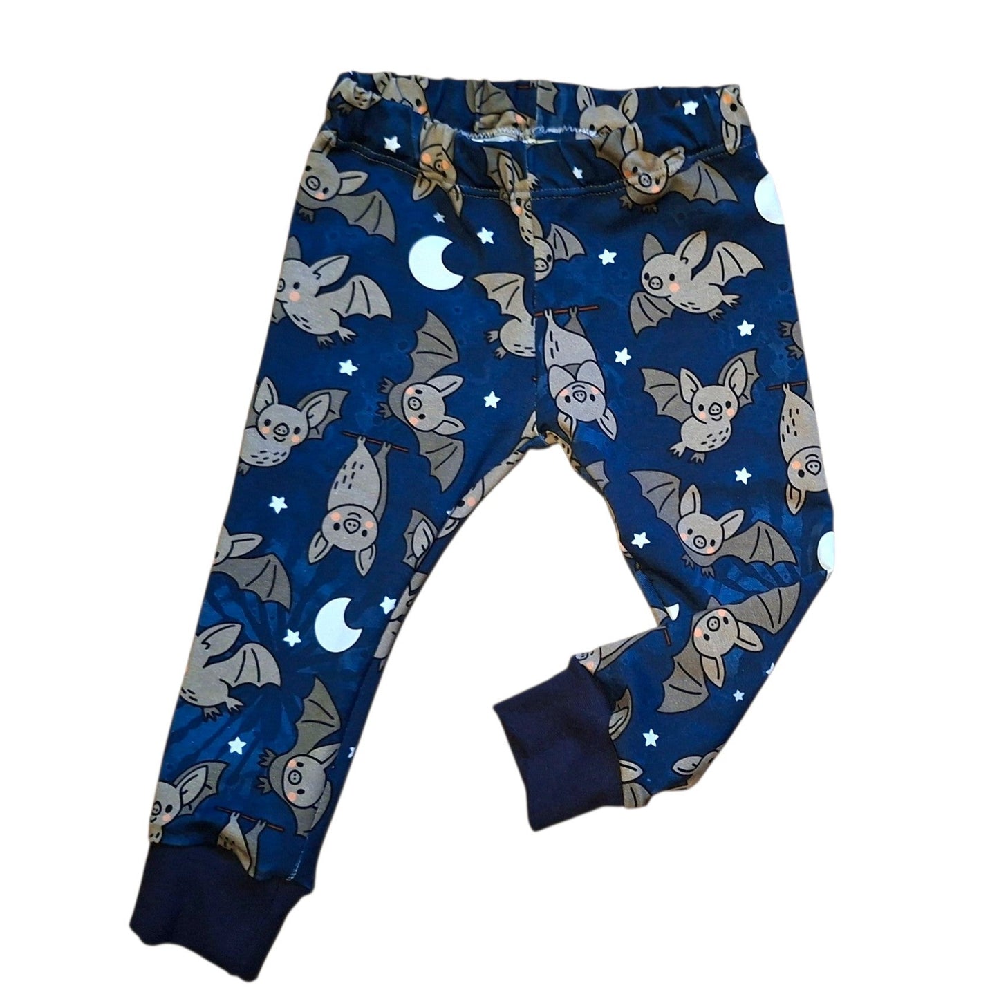 A pair of children's long pants in navy blue with an all-over print of cartoon bats, crescent moons, and stars, featuring solid navy cuffs.