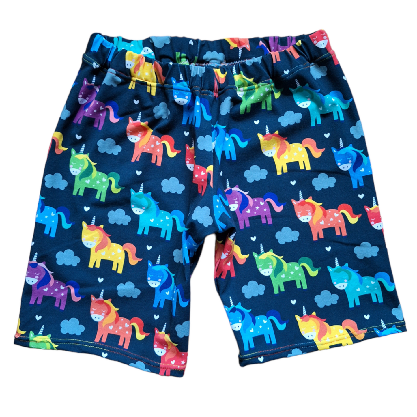 Unicorn print knee length childrens shorts, on a navy blue fabric with multicoloured cartoon style unicorns