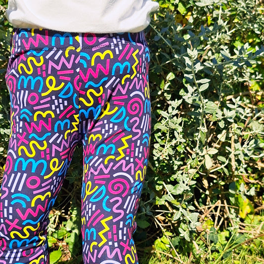 Colorful patterned leggings worn by a person standing in a natural setting.