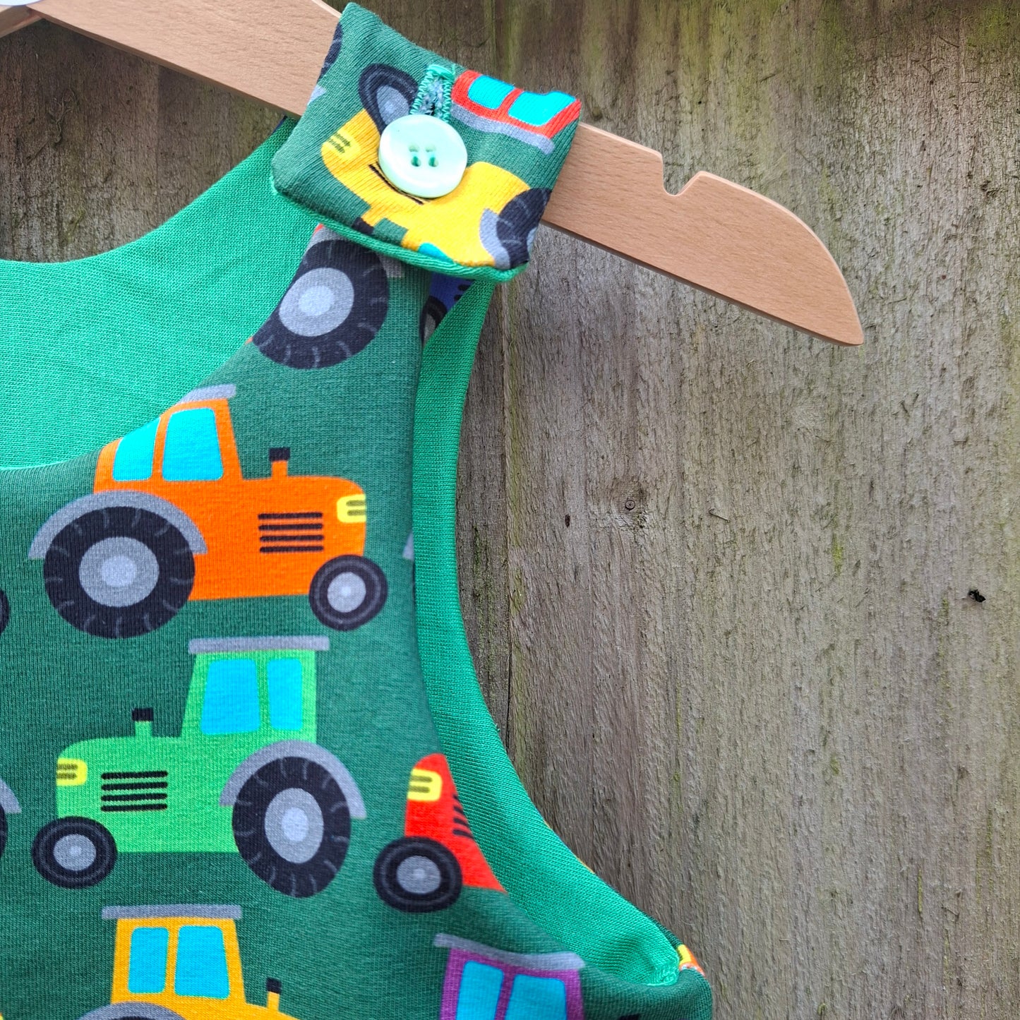 Green children's dungarees featuring rainbow coloured tractors