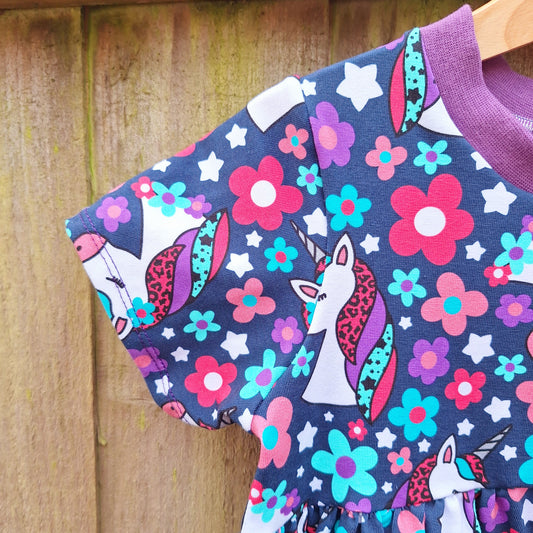 Navy blue child's dress with pink and purple repeating unicorn pattern