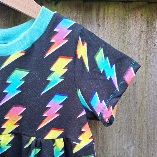 Children's dress with colorful lightning bolt pattern on a wooden background
