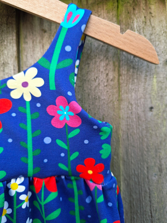 Children's romper in a bright mix of flowers on a blue fabric 