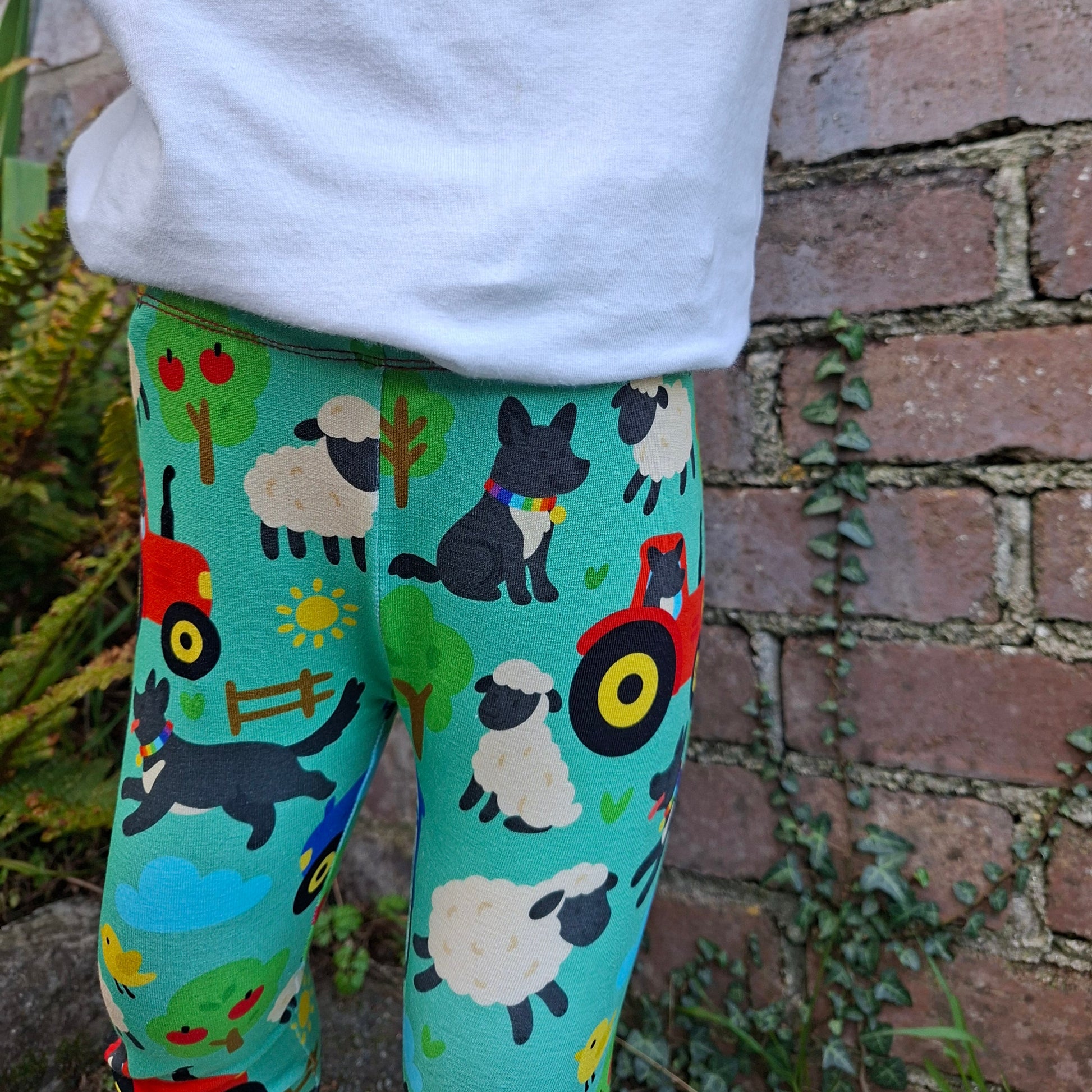 Colorful leggings with animal patterns worn by a person against a brick wall.