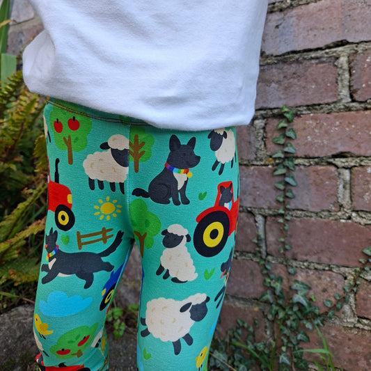 Colorful leggings with animal patterns worn by a person against a brick wall.