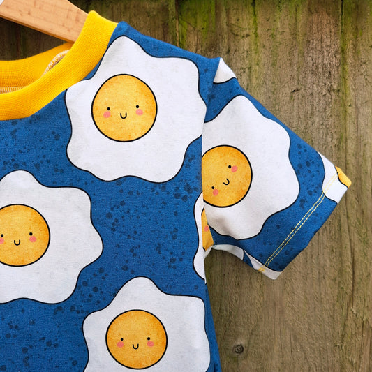 Children's shirt with cartoon egg design on a wooden surface