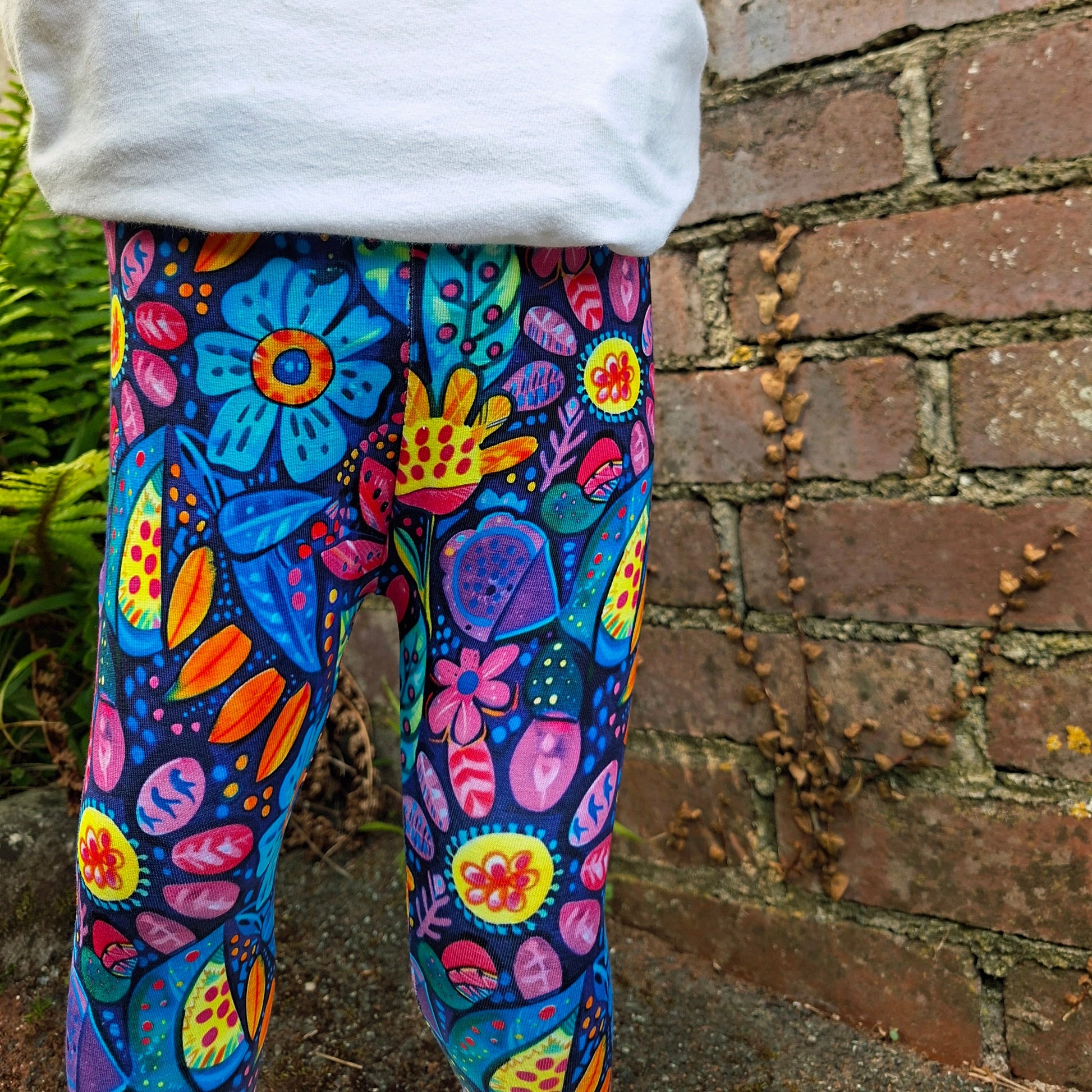 Colorful floral-patterned leggings  on a white pillow against a brick wall background