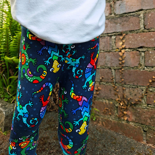 Colorful lizard-patterned leggings worn by a child on a brick path.