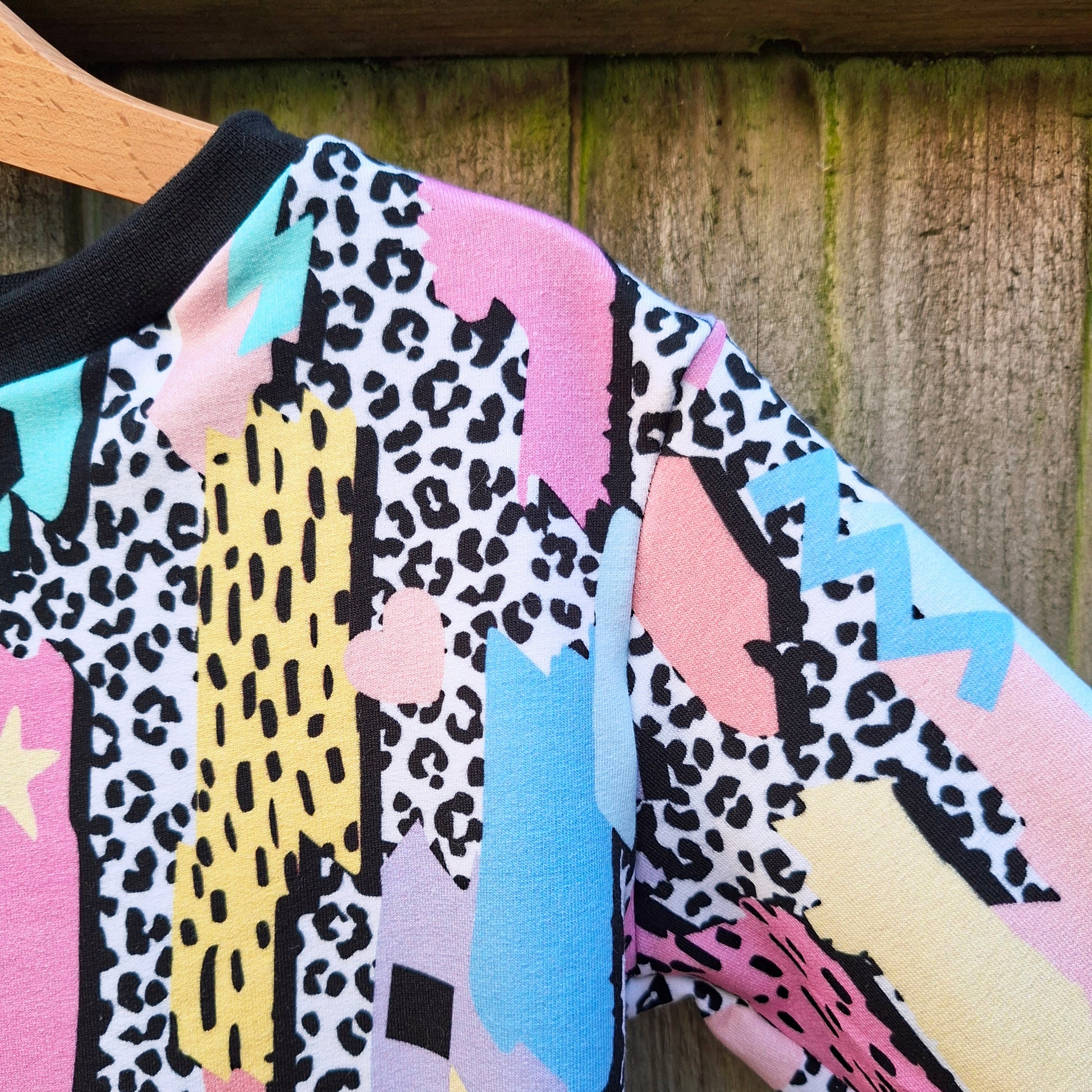 Colorful patterned garment on a wooden hanger against a wooden background