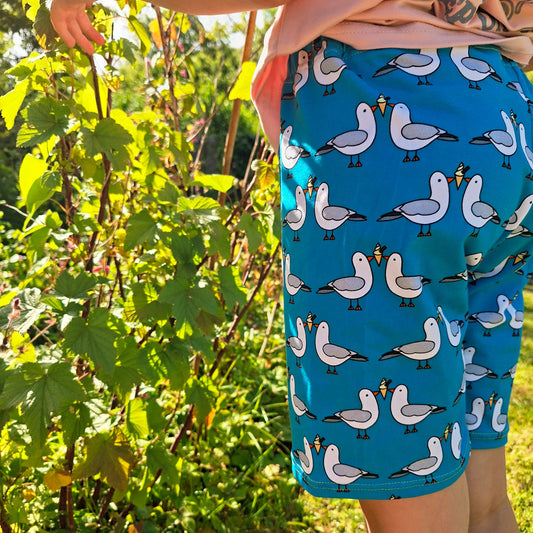 Child wearing blue shorts with seagull pattern in a garden setting