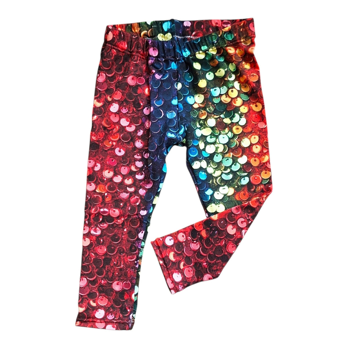 A pair of children's leggings covered in large, shiny sequins that transition through a rainbow of colors including red, pink, blue, green, yellow, and orange, laid flat on a white background.