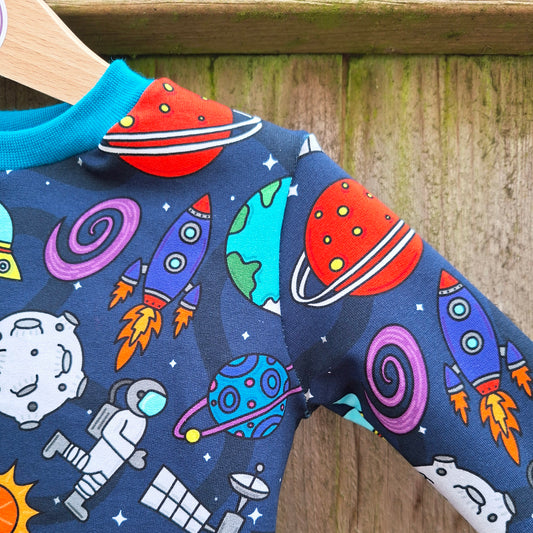 Children's outfit with space-themed pattern on a wooden background
