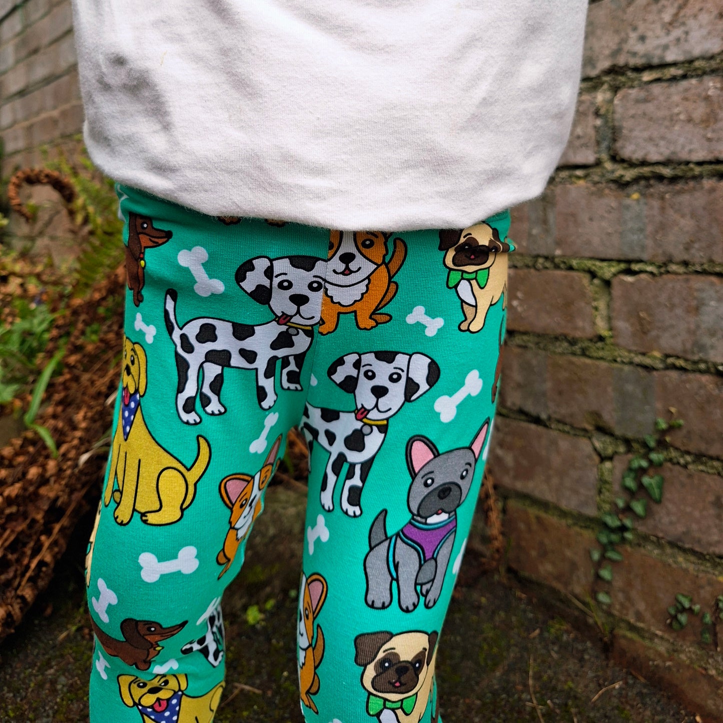 Leggings with dog pattern worn by a person against a brick wall.