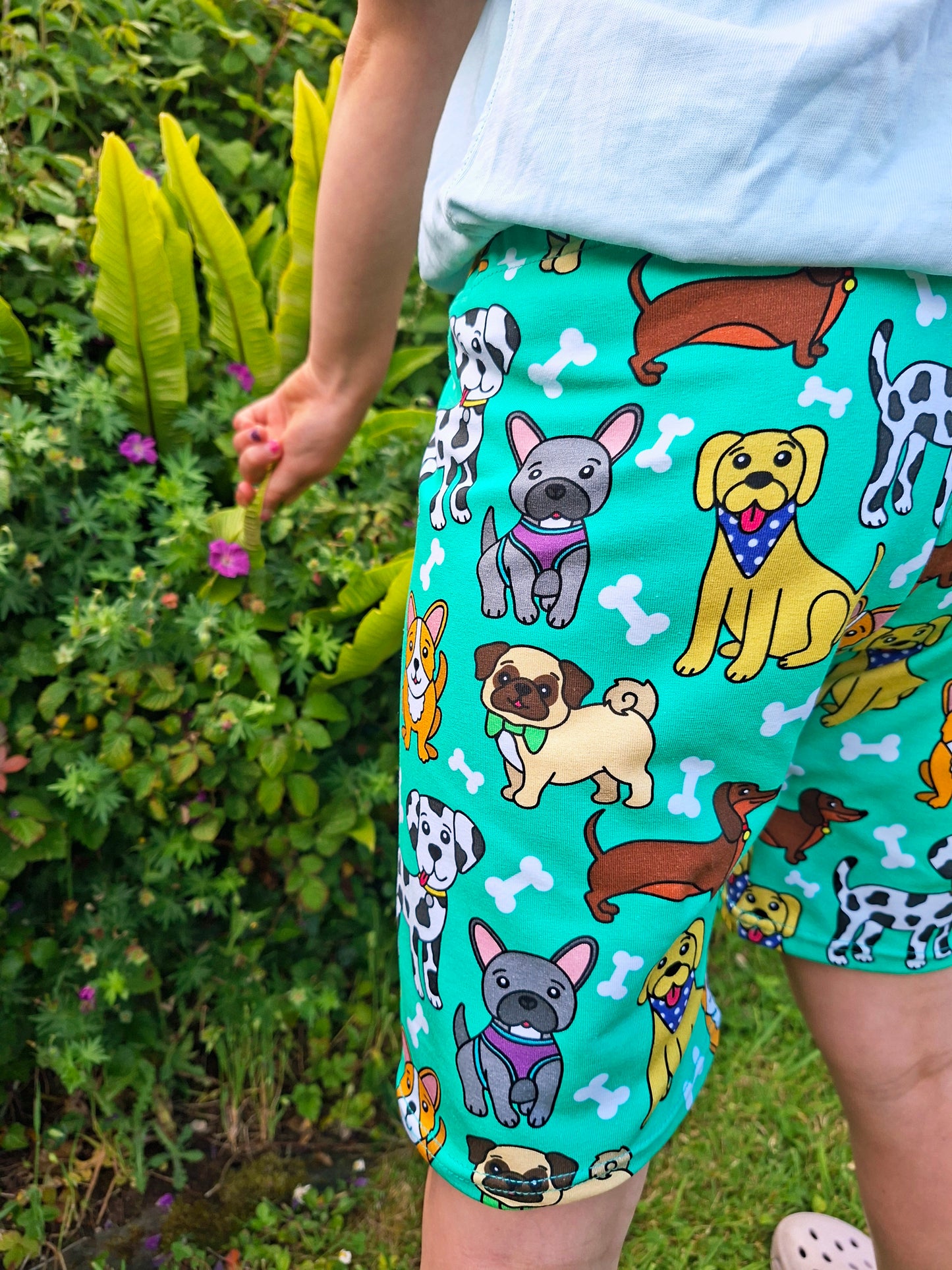 Child wearing shorts with dog pattern in a garden setting