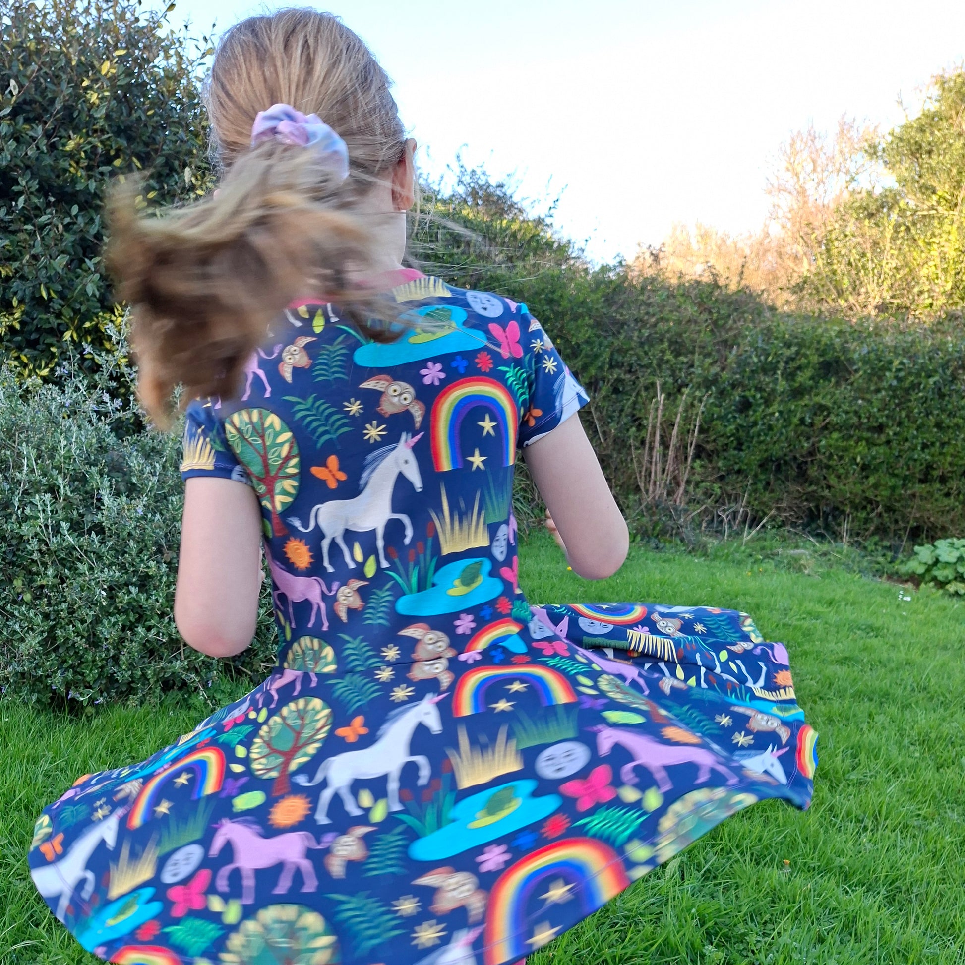 Colorful children's dress with unicorn and rainbow pattern worn by a young child 