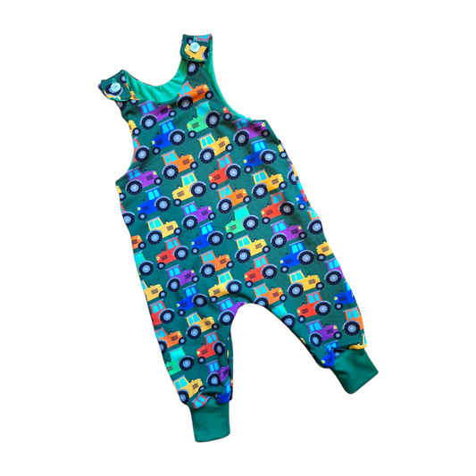 Children's dungarees in a green fabric with rainbow coloured tractors 